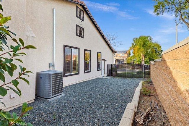 rear view of property featuring a fenced backyard, central AC unit, and stucco siding