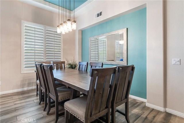 dining room featuring baseboards, visible vents, an inviting chandelier, and wood finished floors