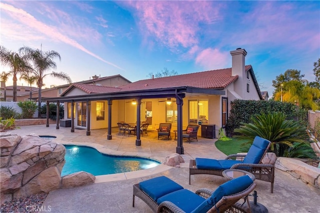 back of property at dusk with a patio, a fenced backyard, an outdoor hangout area, a tile roof, and a chimney