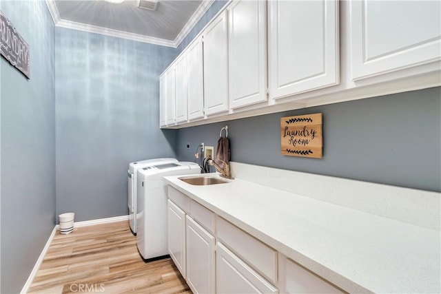 washroom with cabinet space, baseboards, ornamental molding, washer and dryer, and light wood-type flooring