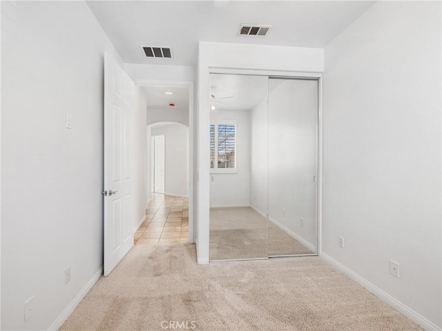 unfurnished bedroom featuring a closet and light colored carpet