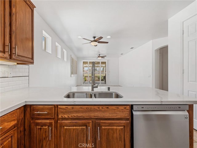 kitchen featuring sink, ceiling fan, stainless steel dishwasher, kitchen peninsula, and tasteful backsplash