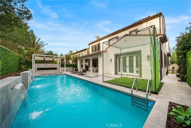 rear view of house with french doors, pool water feature, a fenced in pool, and a patio area