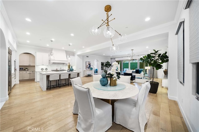 dining space with light wood-type flooring, sink, and ornamental molding