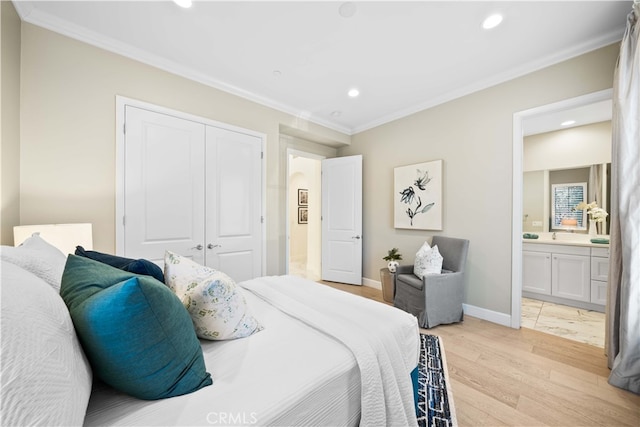 bedroom featuring a closet, ensuite bathroom, crown molding, and light hardwood / wood-style flooring