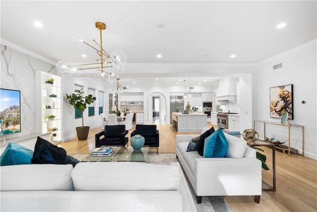 living room featuring a notable chandelier, light hardwood / wood-style flooring, and crown molding