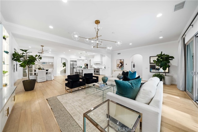 living room with light hardwood / wood-style flooring, crown molding, and a notable chandelier