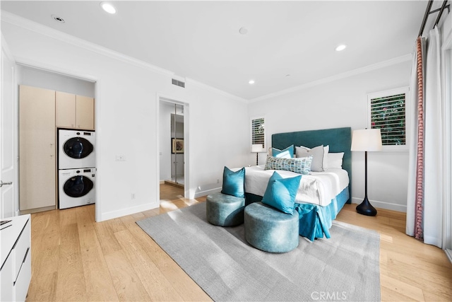 bedroom with stacked washing maching and dryer, crown molding, and light hardwood / wood-style floors