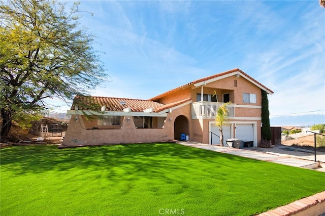 back of house featuring a lawn, a garage, and a balcony