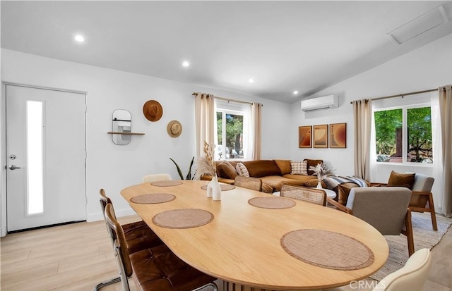 dining space featuring vaulted ceiling, a wall mounted air conditioner, and light hardwood / wood-style flooring