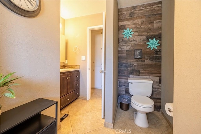 bathroom featuring wooden walls, vanity, toilet, and tile patterned floors