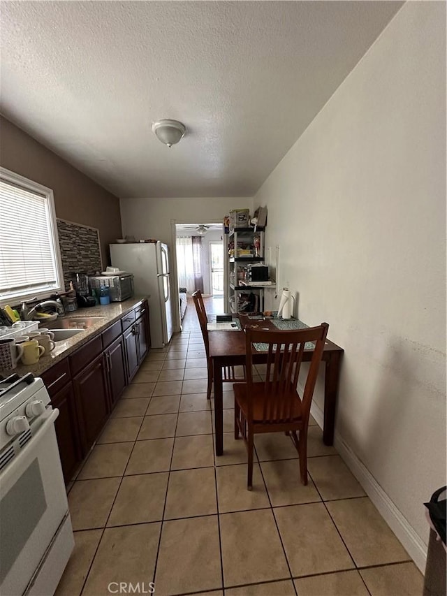 tiled dining room with ceiling fan, sink, and a textured ceiling