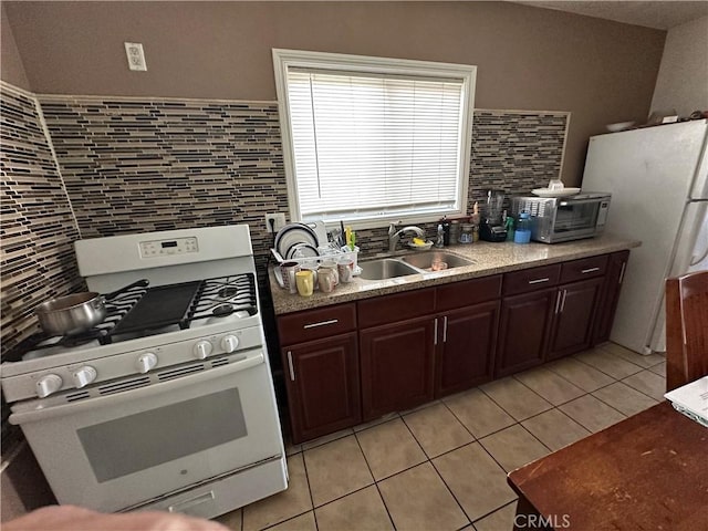 kitchen featuring sink, backsplash, light tile patterned floors, dark brown cabinets, and white appliances