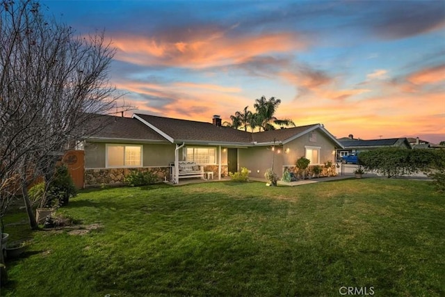 back house at dusk featuring a lawn