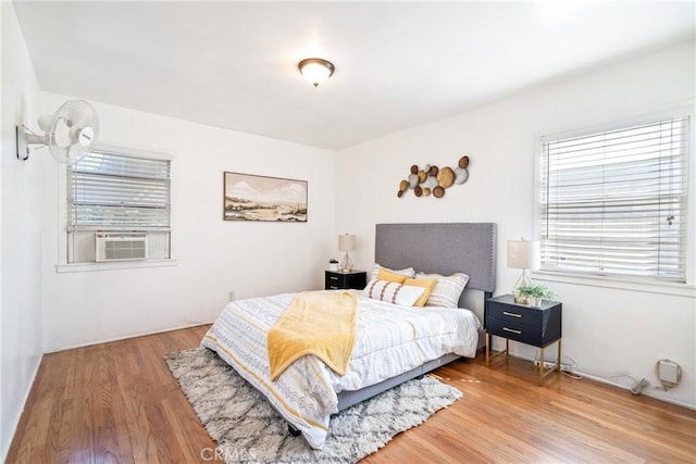 bedroom with multiple windows, cooling unit, and wood finished floors