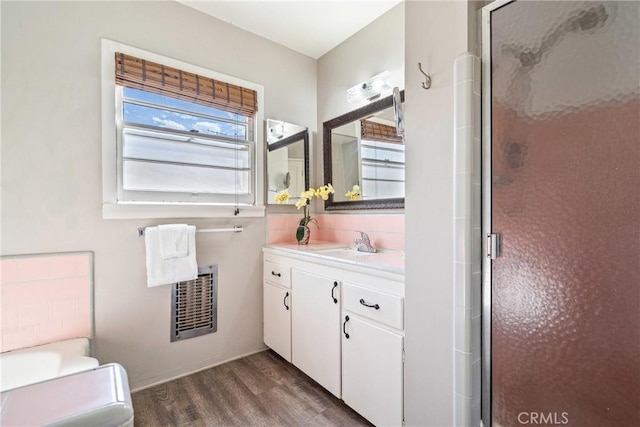 bathroom with visible vents, toilet, wood finished floors, vanity, and a shower stall