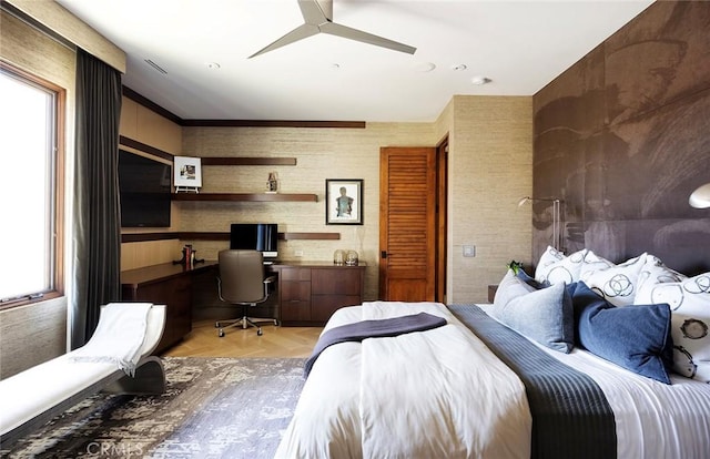 bedroom featuring light parquet flooring, built in desk, and ceiling fan