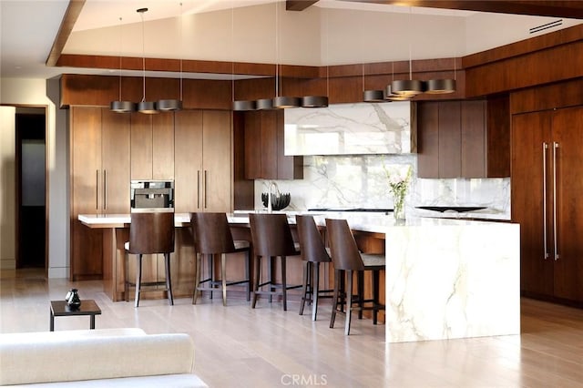 kitchen with a large island, decorative backsplash, a breakfast bar, and premium range hood