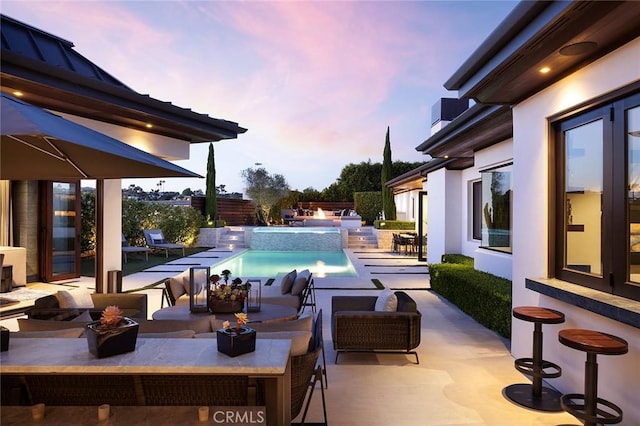 pool at dusk featuring a patio area