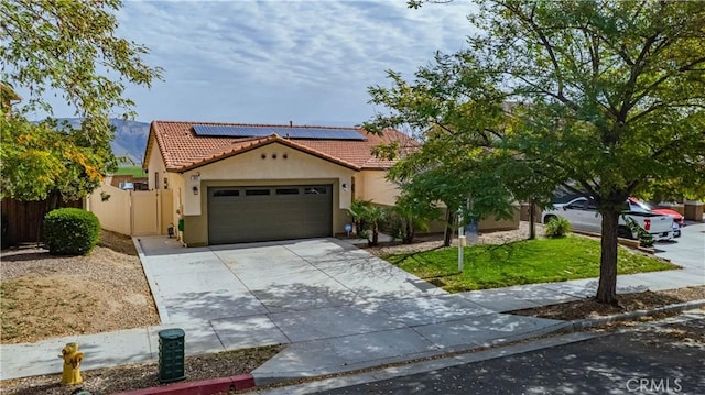 mediterranean / spanish-style house featuring stucco siding, roof mounted solar panels, fence, and a tiled roof