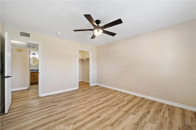 unfurnished bedroom with a walk in closet, light hardwood / wood-style flooring, a closet, and ceiling fan