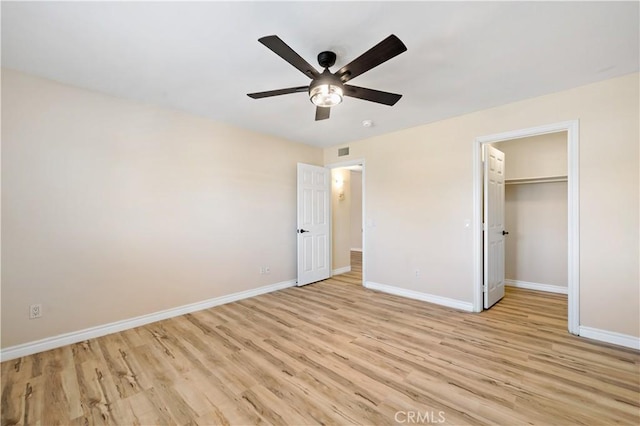 unfurnished bedroom with ceiling fan, light hardwood / wood-style floors, a closet, and a walk in closet