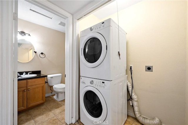 clothes washing area featuring stacked washer / drying machine, sink, and light tile patterned floors