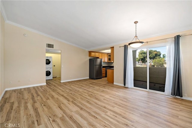 unfurnished living room with light hardwood / wood-style flooring, ornamental molding, and stacked washing maching and dryer