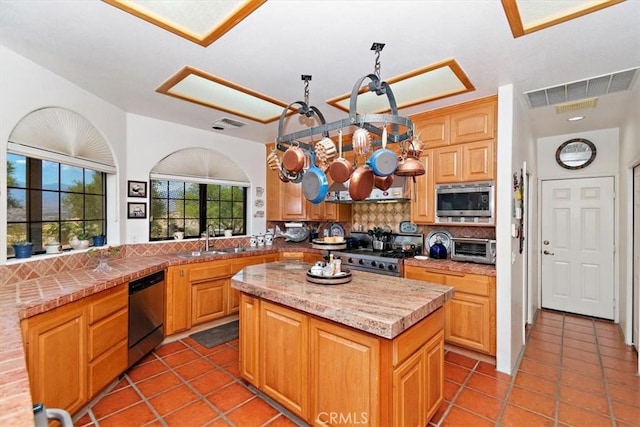 kitchen with light tile patterned flooring, sink, decorative backsplash, a center island, and stainless steel appliances