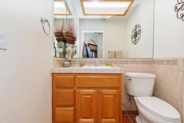 bathroom featuring vanity, tile walls, and toilet