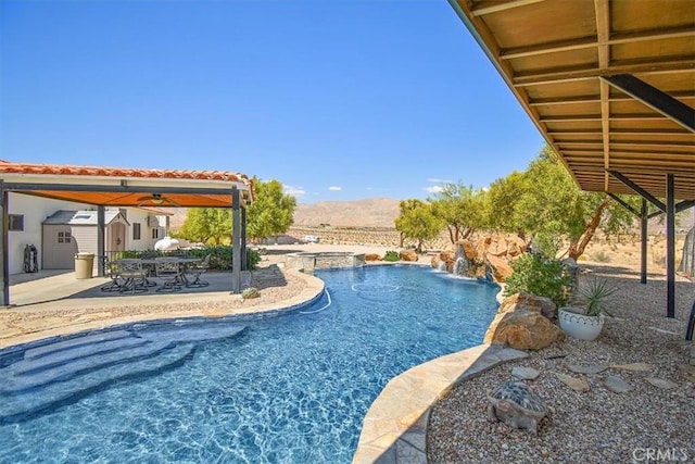 view of pool featuring a mountain view, a patio area, ceiling fan, and a storage unit