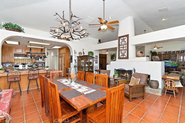 dining space featuring light tile patterned floors, ceiling fan with notable chandelier, and high vaulted ceiling