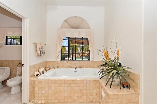 bathroom featuring a relaxing tiled tub, a bidet, tile patterned floors, and toilet