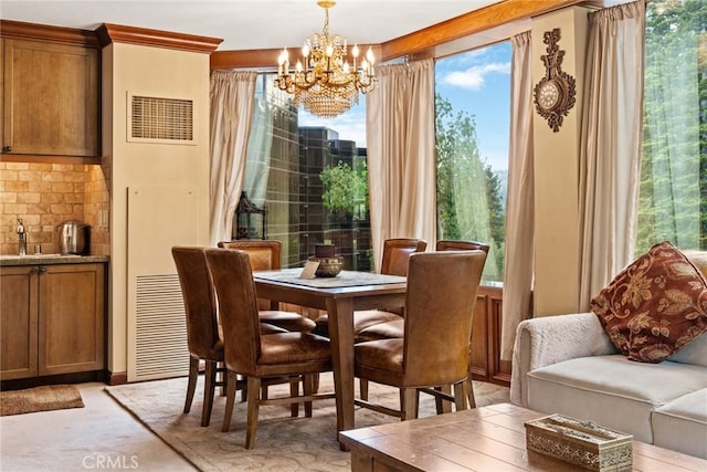 carpeted dining area featuring crown molding, sink, and an inviting chandelier