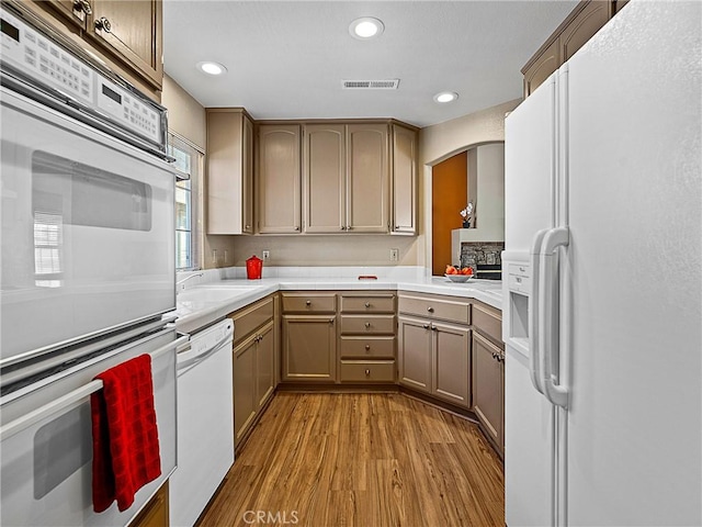 kitchen with light countertops, recessed lighting, wood finished floors, white appliances, and a sink