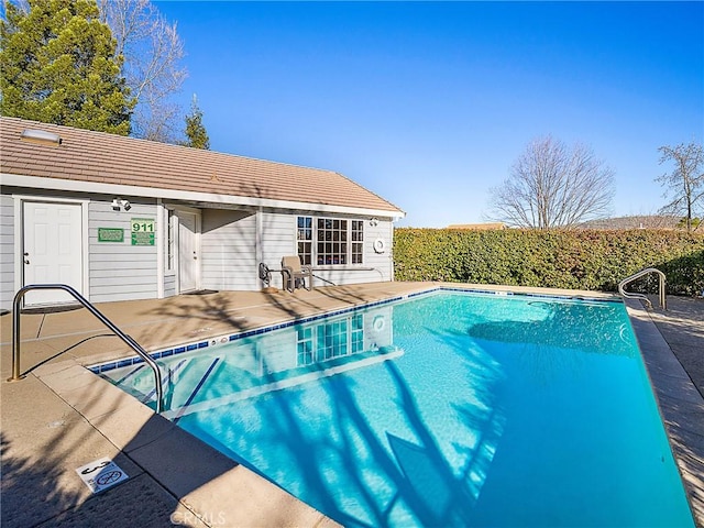 view of swimming pool with an outdoor structure, a storage structure, a fenced in pool, and a patio