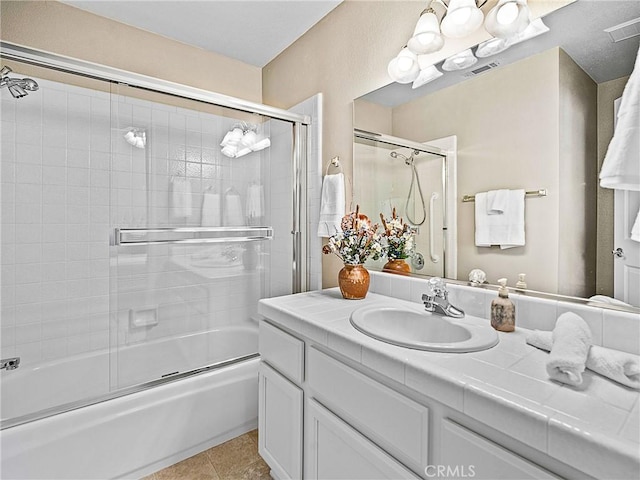 bathroom featuring tile patterned floors, visible vents, vanity, and bath / shower combo with glass door