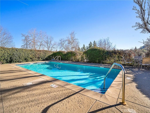 pool with a patio and fence