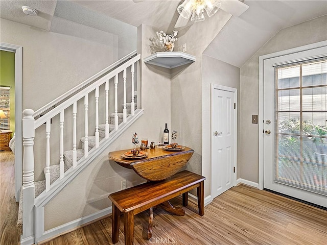 interior space with lofted ceiling, stairs, baseboards, and wood finished floors