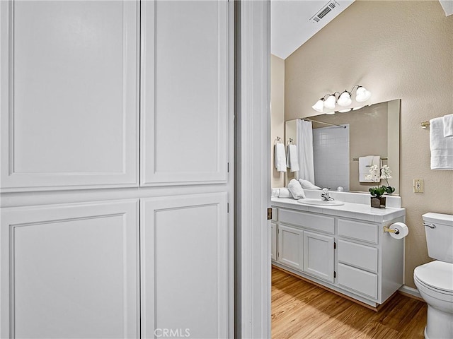 full bath with visible vents, toilet, wood finished floors, a shower with shower curtain, and vanity