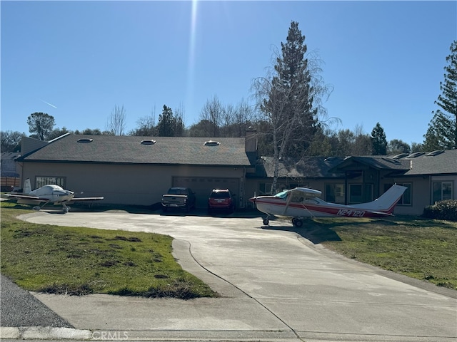 view of property exterior with a yard, an attached garage, and driveway