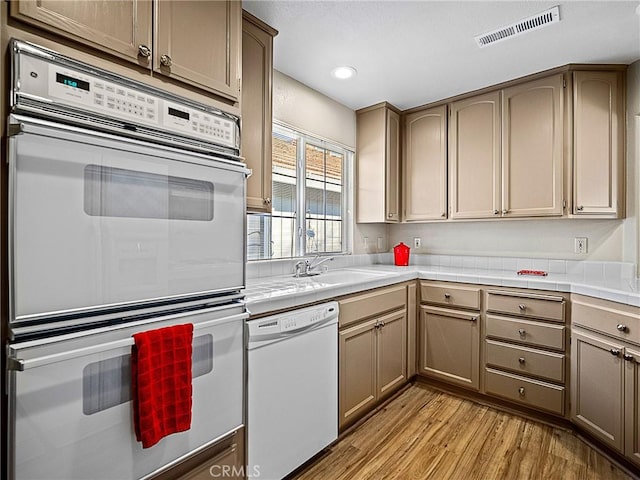 kitchen featuring visible vents, tile countertops, recessed lighting, light wood-style flooring, and white appliances