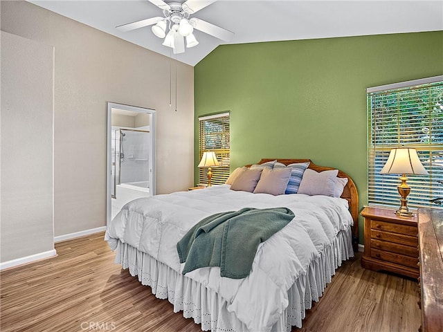 bedroom with vaulted ceiling, ensuite bath, baseboards, and wood finished floors