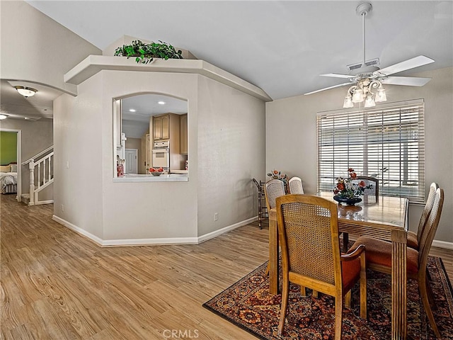 dining space with baseboards, lofted ceiling, and light wood-style floors