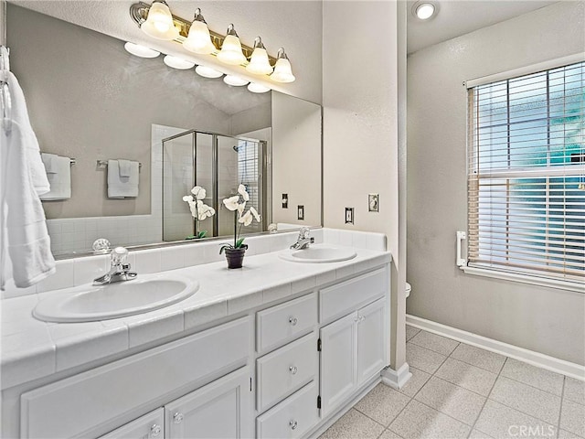 full bathroom with a healthy amount of sunlight, a shower stall, and a sink