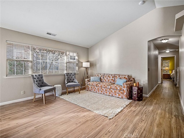 living room with visible vents, baseboards, lofted ceiling, and wood finished floors