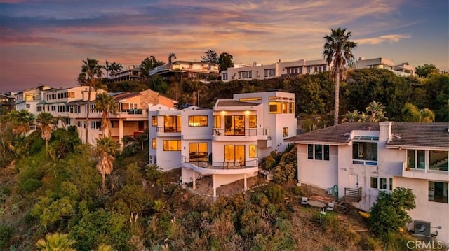 rear view of house with a residential view, a balcony, and stucco siding