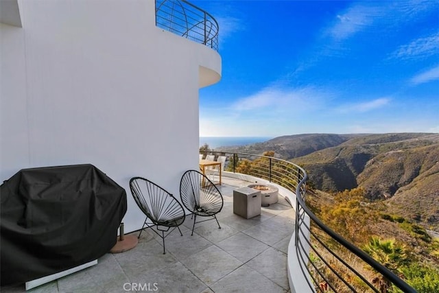balcony featuring a fire pit, a mountain view, and a grill