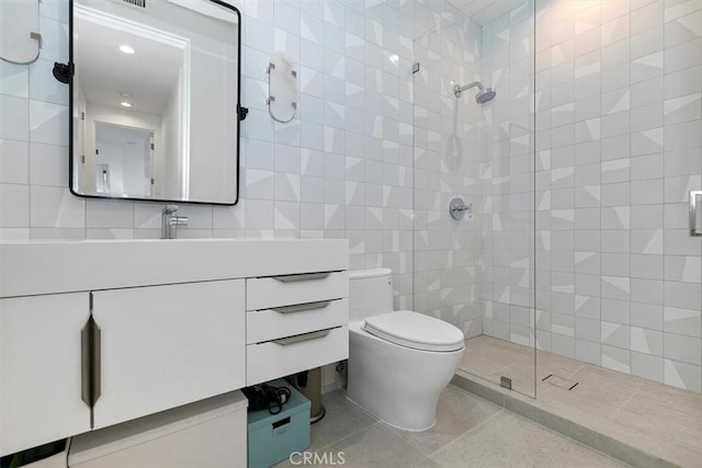 bathroom with toilet, tiled shower, tile walls, and vanity