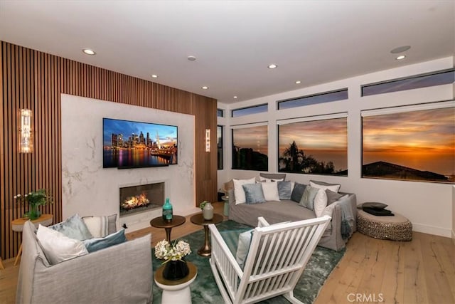 living room with recessed lighting, a high end fireplace, and hardwood / wood-style floors